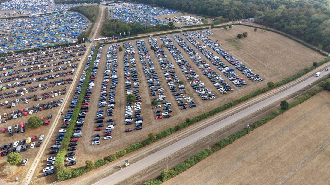 Aerial view of a full festival car park laid out in neat rows beside the campsite