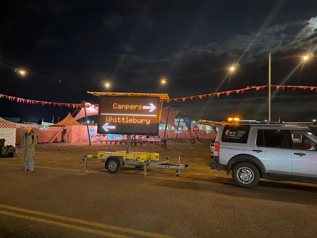 IF-IT Events 4x4 parked beside an illuminated sign directing campers at night