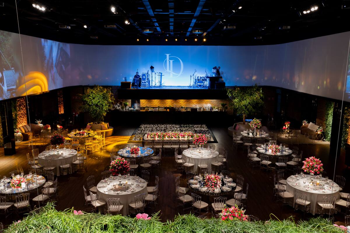 Elegant corporate gala dinner setup with round tables, floral centrepieces and a stage